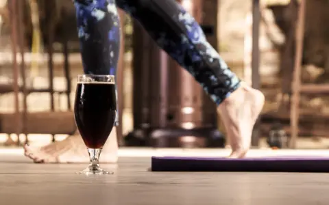 Szklanka ciemnego piwa obok maty do ćwiczeń. Czy to koniec treningu, czy nagroda? Alkohol a siłownia – dylemat.