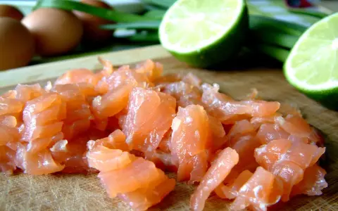 Pokrojony łosoś, jajka i limonka na desce. Idealne składniki na pyszny omlet z łososiem.