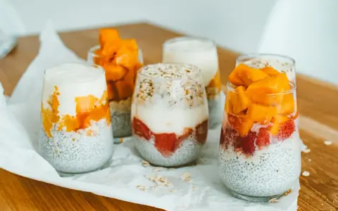Pyszny deser chia z mango i truskawkami w szklankach, ułożony warstwowo z jogurtem i płatkami owsianymi.