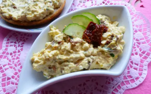 Pyszna pasta jajeczna z suszonymi pomidorami, ozdobiona plasterkami ogórka i pomidorów. Idealna na kanapki.