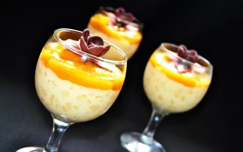 Pyszny deser z tapioki z mango, udekorowany czekoladowym kwiatkiem. Idealny na letnie popołudnie.