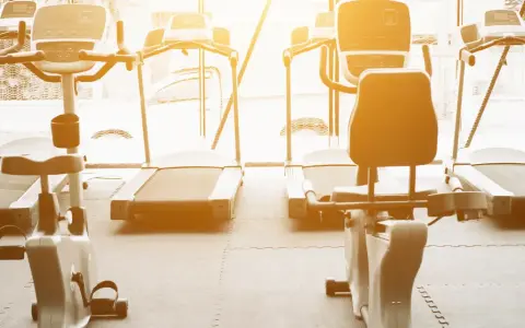 Rzędy bieżni i rowerów stacjonarnych czekają na trening. Idealne miejsce na cardio na siłowni, by poczuć energię.