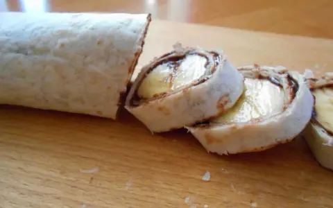 Słodka tortilla z bananem i czekoladą, pokrojona w rolki, wygląda jak pyszny deser.