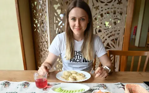 Kobieta przy stole z pierogami i surówką. Posiłek to świetny sposób, jak szybko uzupełnić białko w organizmie.