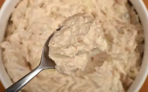 Łyżka pełna kremowej pasty z tuńczyka, gotowa do podania. Idealna na kanapki lub jako dodatek.