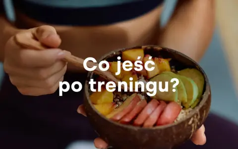 Miseczka z owocami i napisem "Co jeść po treningu?". Zdrowy posiłek regeneracyjny.
