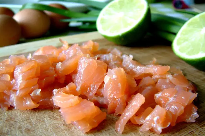 Pokrojony łosoś, jajka i limonka na desce. Idealne składniki na pyszny omlet z łososiem.