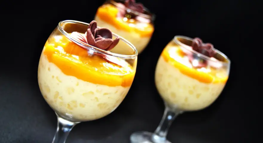 Pyszny deser z tapioki z mango, udekorowany czekoladowym kwiatkiem. Idealny na letnie popołudnie.