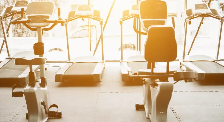 Rzędy bieżni i rowerów stacjonarnych czekają na trening. Idealne miejsce na cardio na siłowni, by poczuć energię.