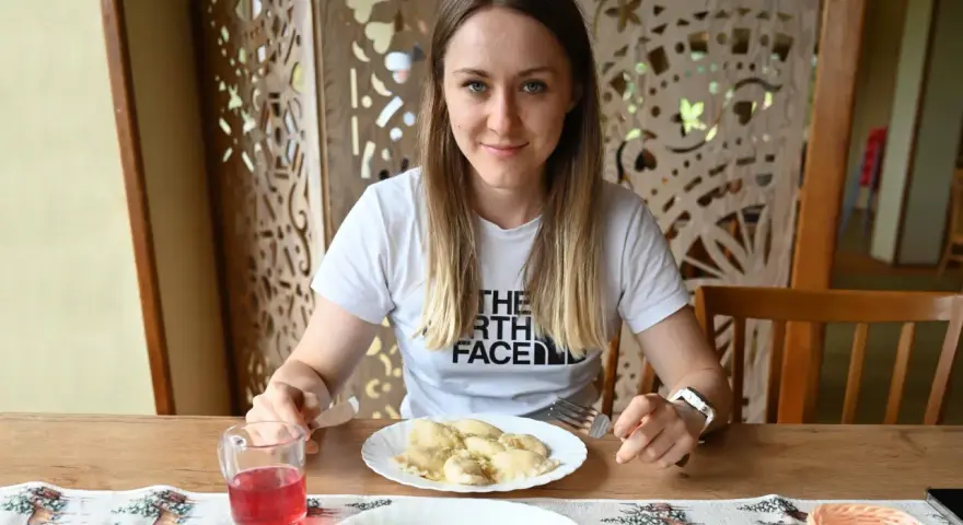 Kobieta przy stole z pierogami i surówką. Posiłek to świetny sposób, jak szybko uzupełnić białko w organizmie.