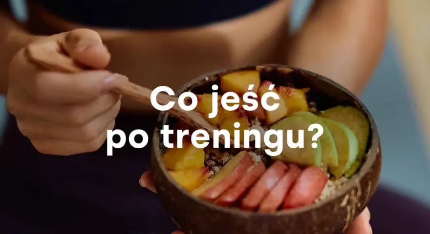 Miseczka z owocami i napisem "Co jeść po treningu?". Zdrowy posiłek regeneracyjny.